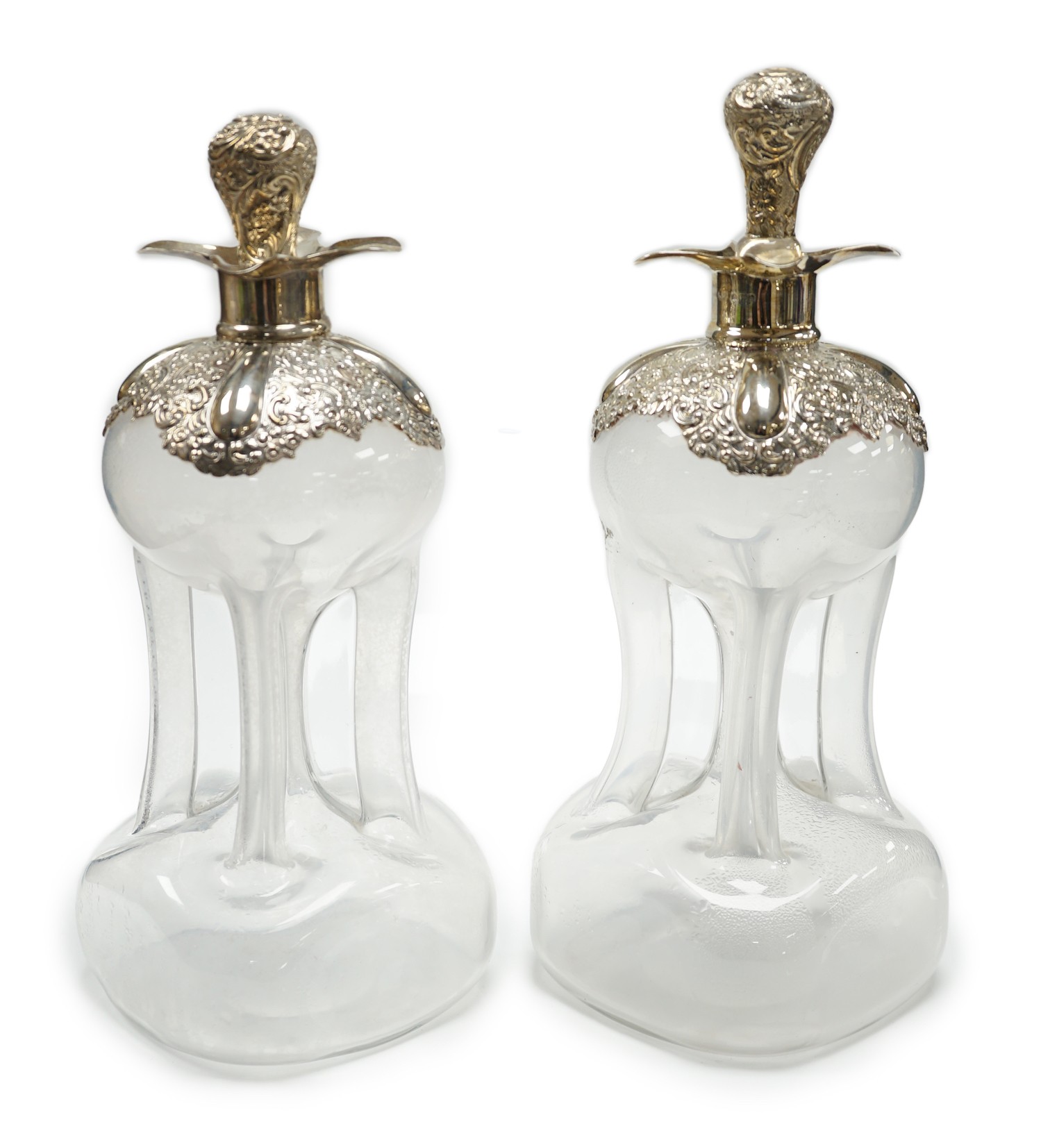 A pair of Edwardian silver mounted glass hour glass shaped decanters, William Hutton & Sons, Birmingham, 1906/7, with associated stoppers, height 23.9cm.